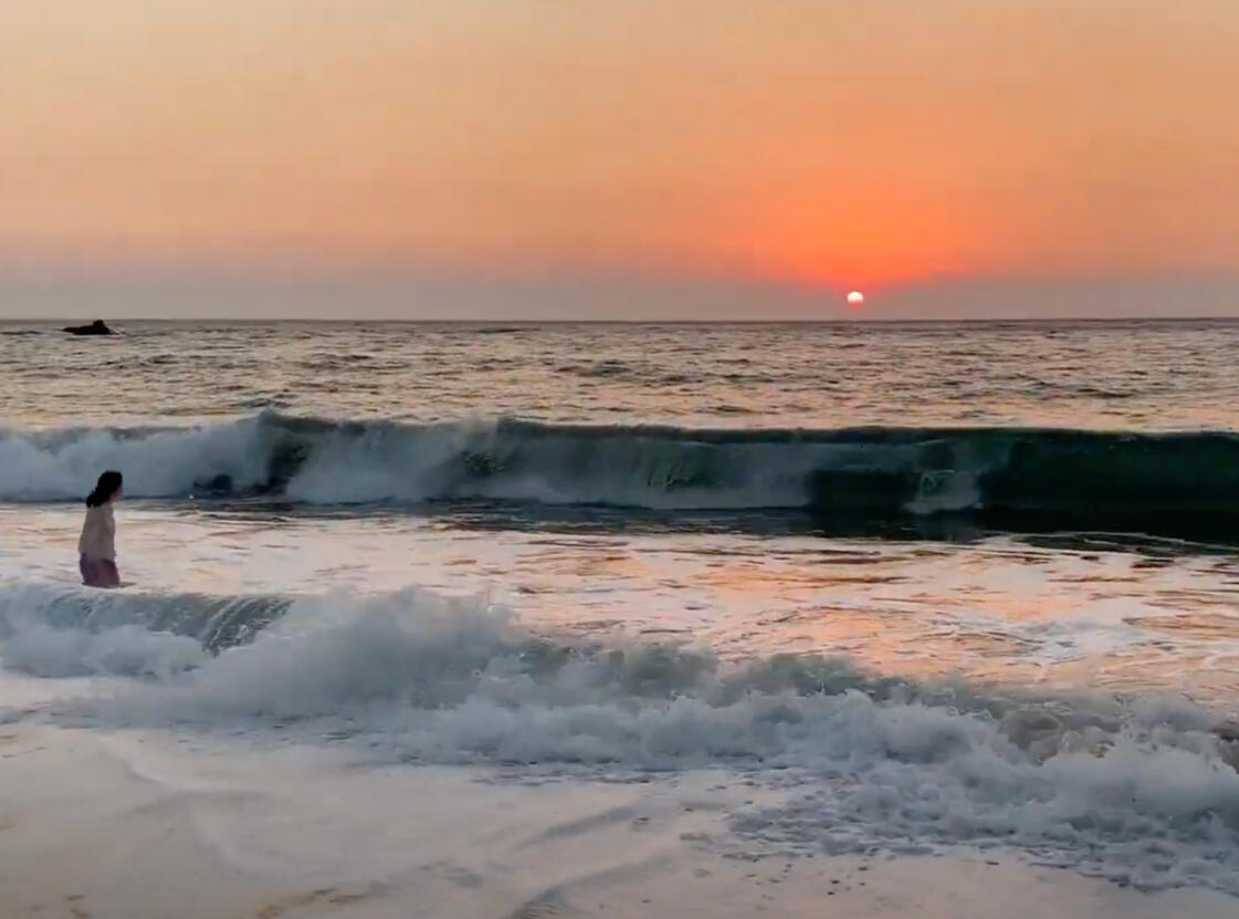 Me at a beach with the sunset gracing the horizon